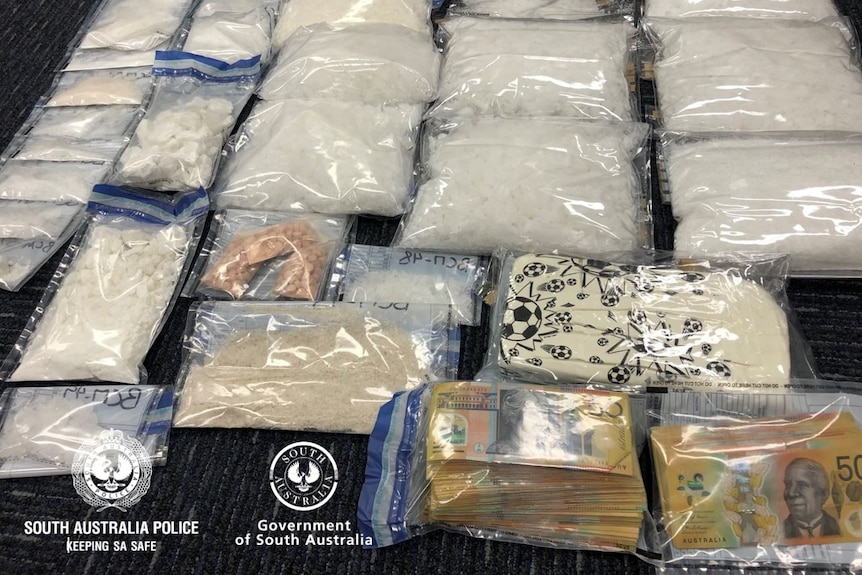 Drugs and cash in plastic bags laid out on a floor.