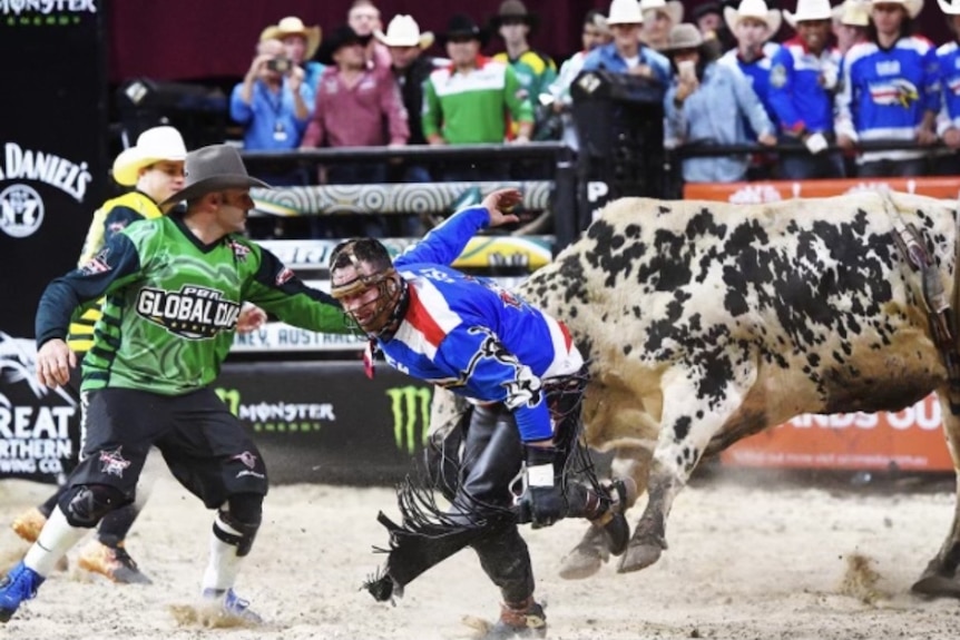 A man runs from a bull as another man steps in to protect him