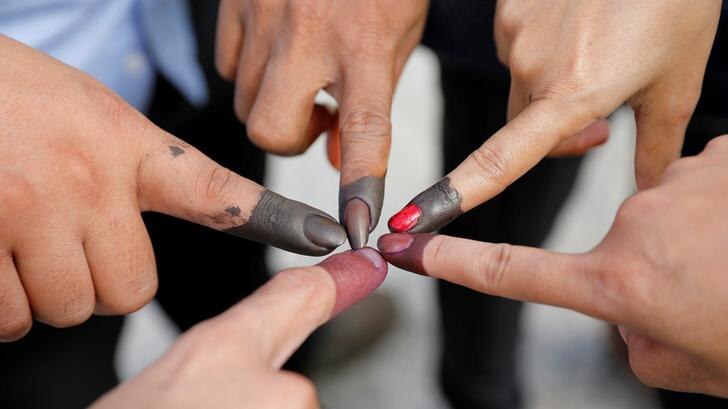 Five people touch their inked fingers together