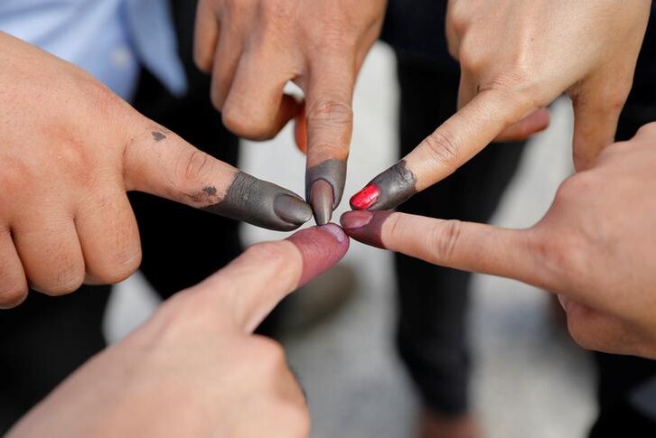 Five people touch their inked fingers together