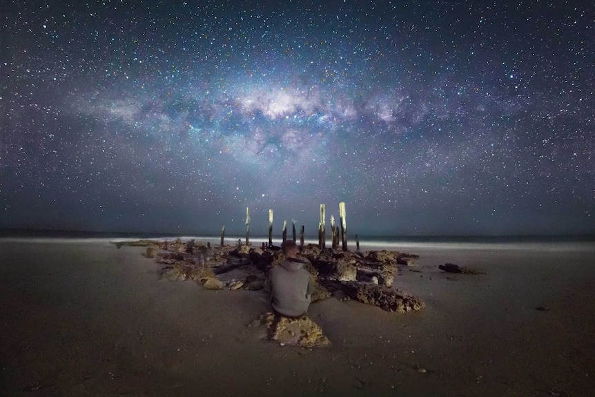 Man on beach under milky way