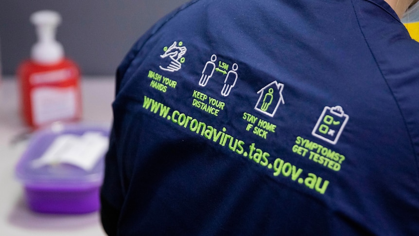 Coronavirus safety messaging on nurse's uniform.