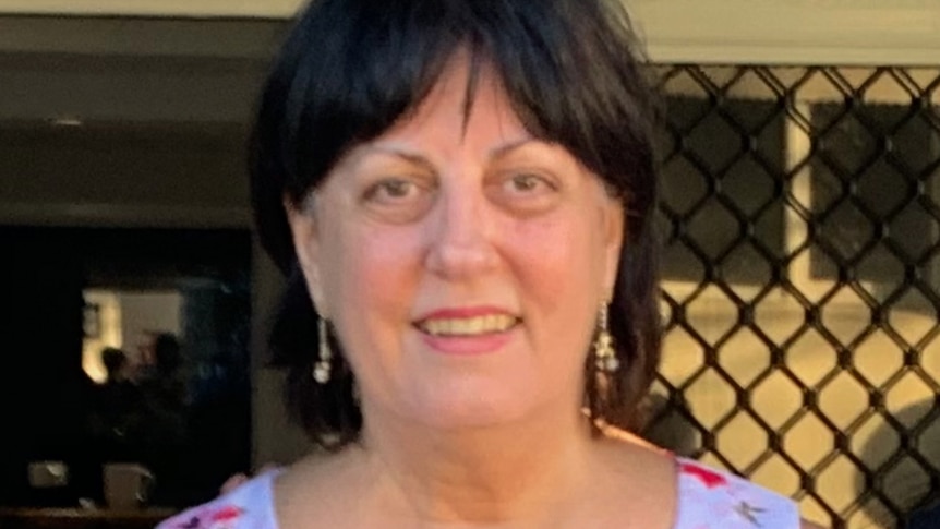 A woman with brown hair and earrings smiles at the camera.