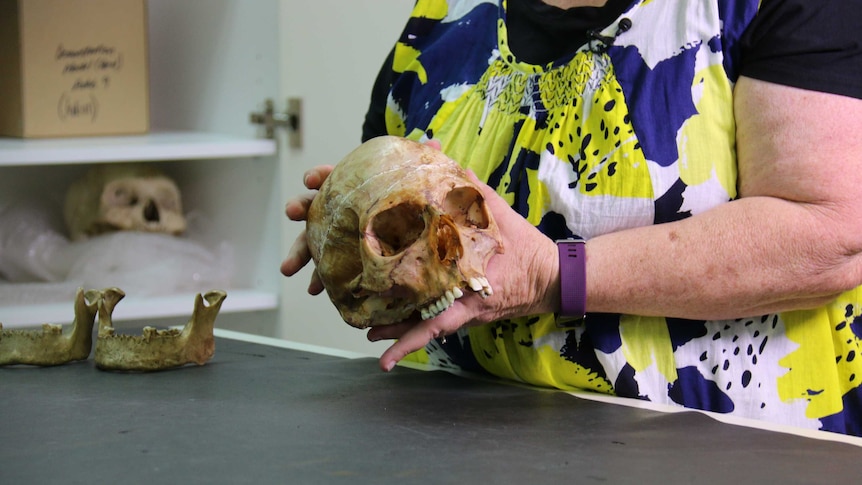 A woman's hands hold a human skull.
