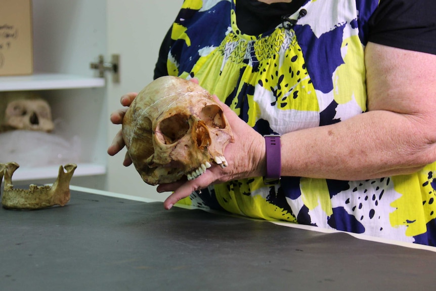 A woman's hands hold a human skull.