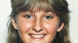 A young girl, Annette Mason, smiles for a portrait photograph. She has a feathered haircut with a fringe