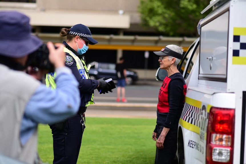 An Extinction Rebellion protester is spoken to by police.