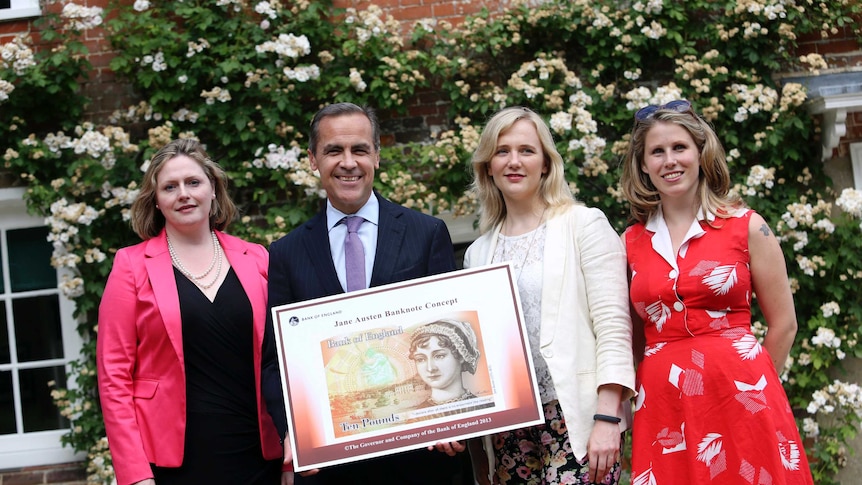 Campaigners pose next to a poster showing the design of the UK's next 10-pound note, which features Jane Austen.