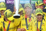 Australian players smile and laugh as they spray champagne and celebrate with a trophy on a podium