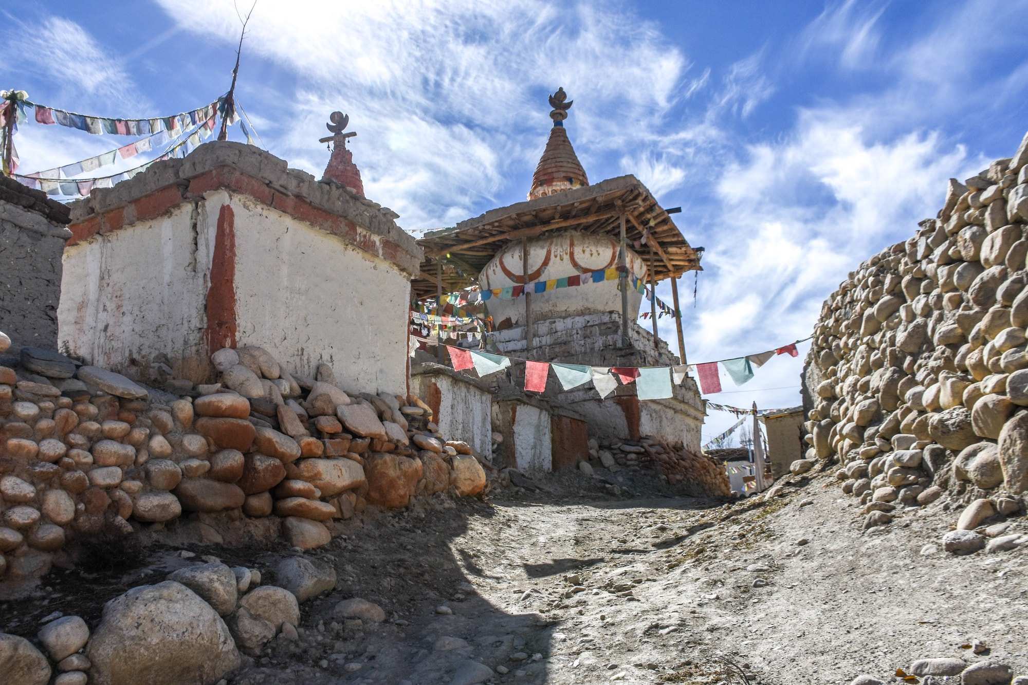 A cobbled street with white-washed clay buildings with rainbow flags