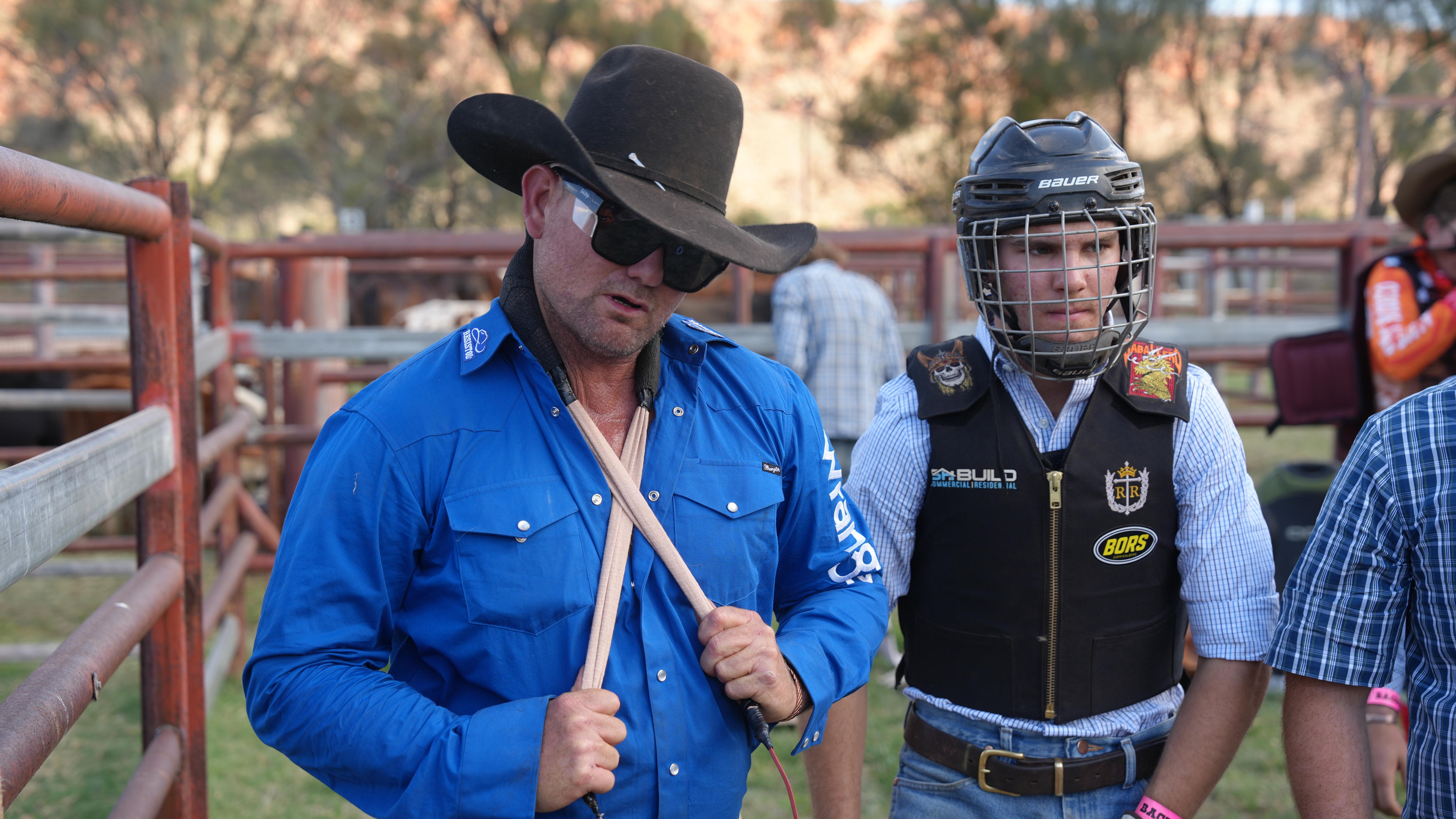 A man in a cowboy hat tugs on a halter around his neck