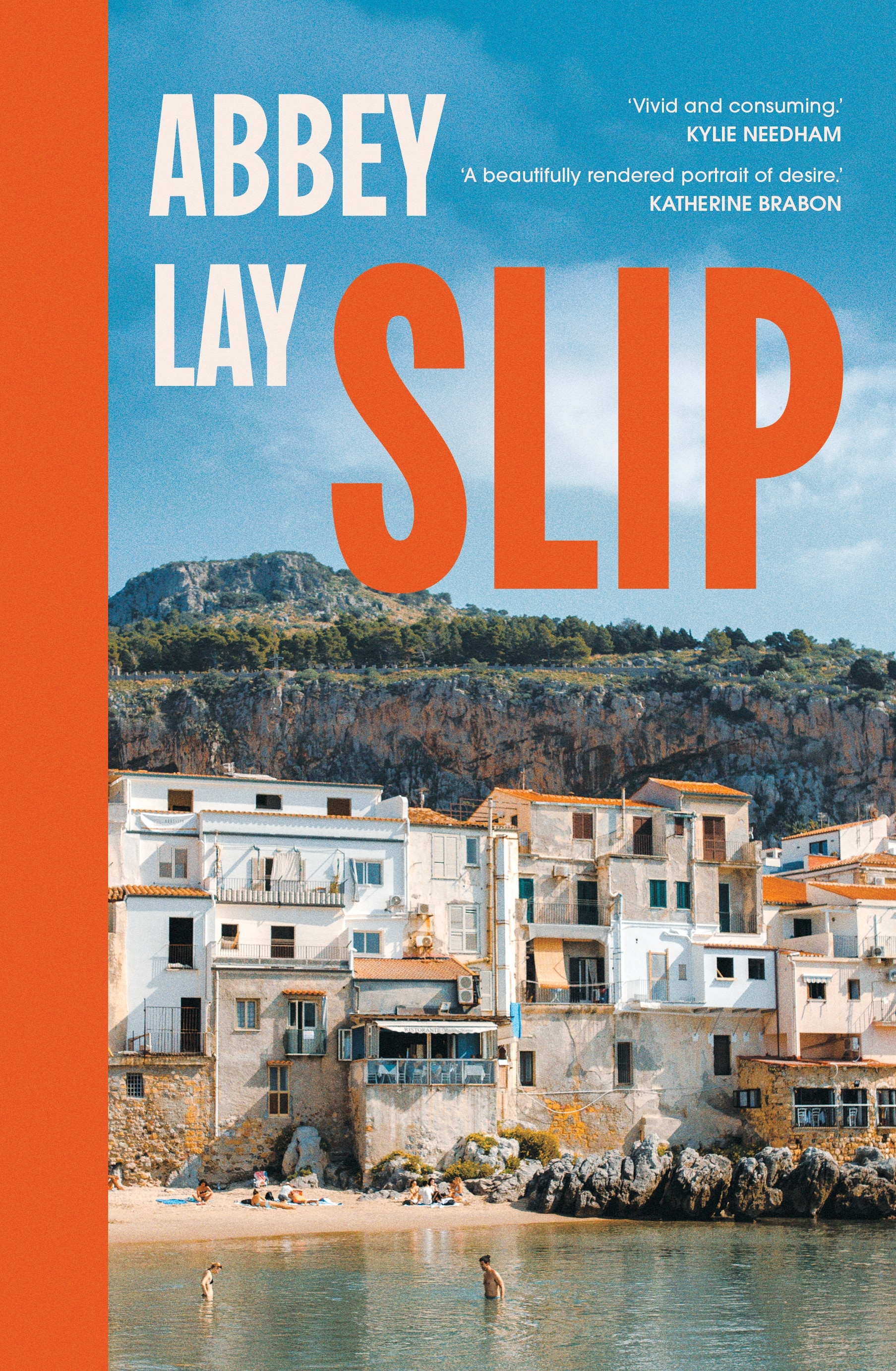 Cover of The Slip by Abbey Lay: a photo of a Sicilian village with white houses overlooking a beach, a tree-covered hill behind.