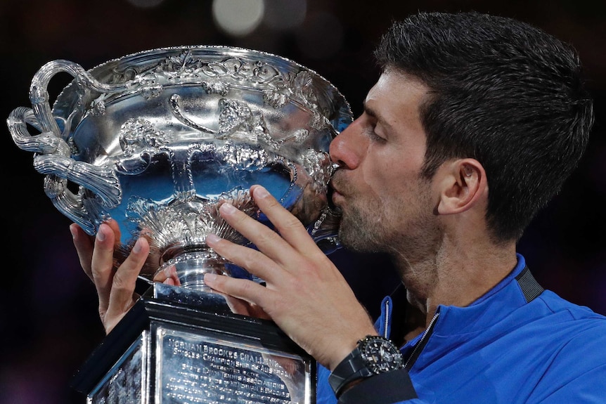Novak Djokovic kisses the Australian Open trophy.