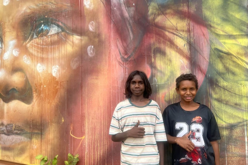 Dwóch rdzennych studentów stojących przed muralem.