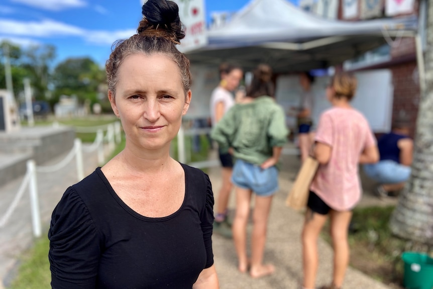 Woman wearing a black shirt standing on the street with people standing in the background.