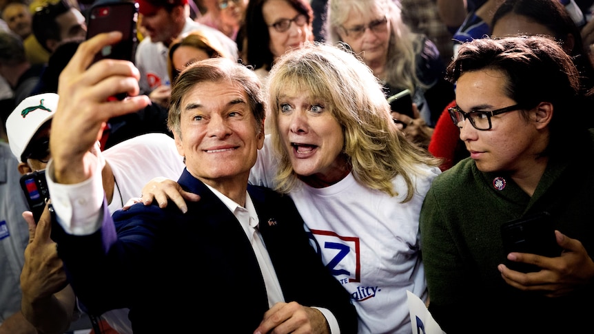 Mehmet Oz takes a selfie with a blond woman 
