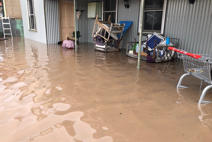 A home with chairs piled high and about half a metre of water flooding the yard
