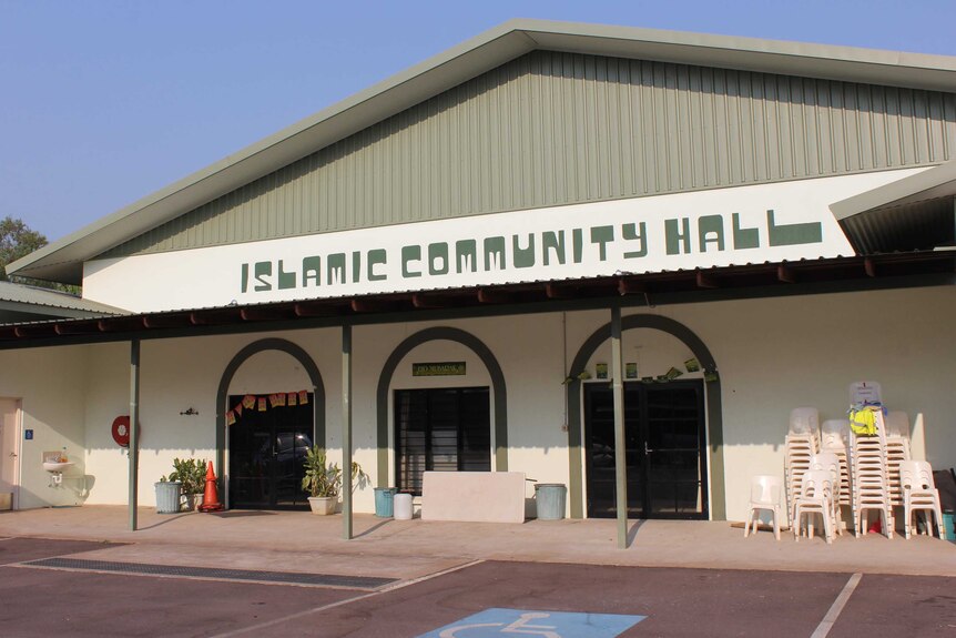 A cream coloured community hall with the words "Islamic Community Hall" written in dark green on the front.