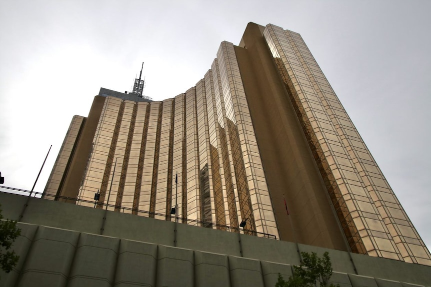 A low angle shot looking up at the gold-coloured tower of a hotel.