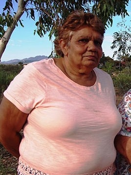 An older Indigenous woman standing outside.