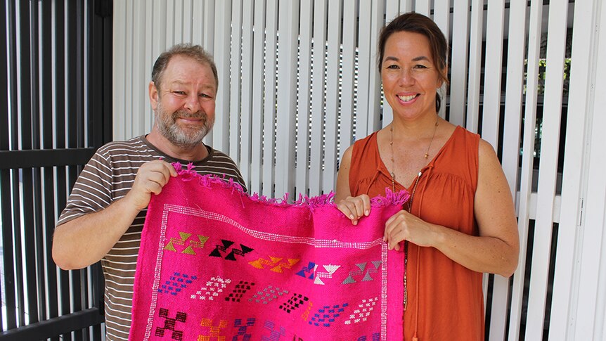 Feng shui master George Bennis holding a pink throw rug with his client Chiu-Ling Lee.