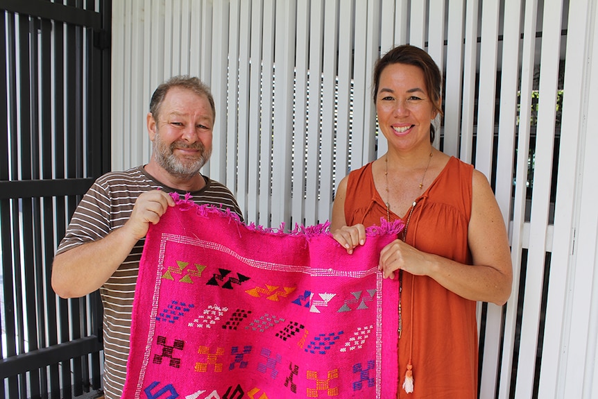 Feng shui master George Bennis holding a pink throw rug with his client Chiu-Ling Lee.