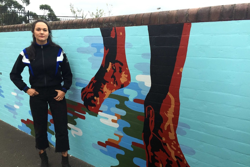 A woman standing in front of the mural.