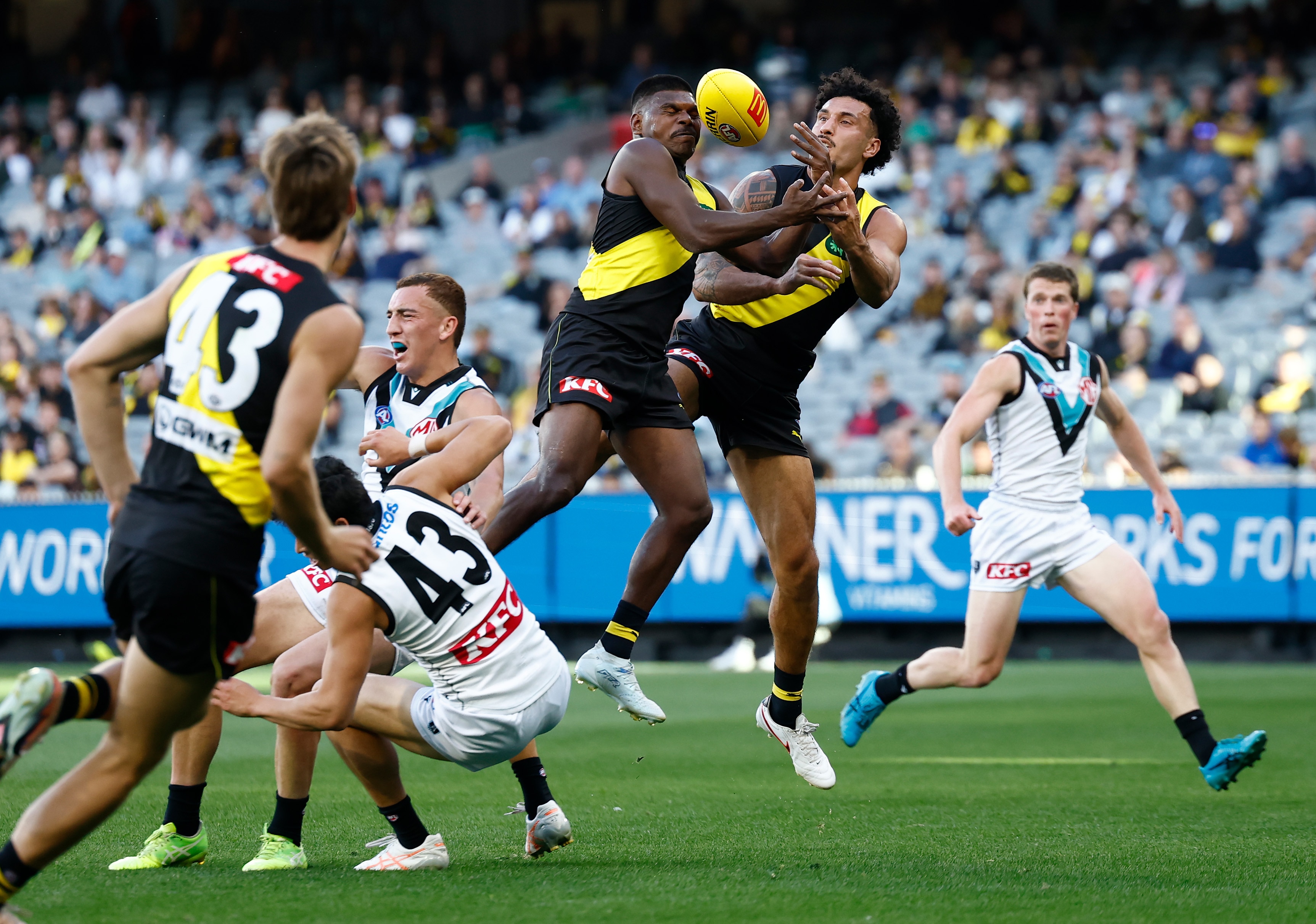 A Richmond AFL player leaps to take a mark as a teammate contests the ball.
