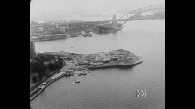 Old photo of aerial view of Sydney Harbor, showing Sydney Opera House under construction