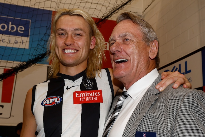Darcy Moore and Peter Moore smile while standing together in the Collingwood dressing rooms