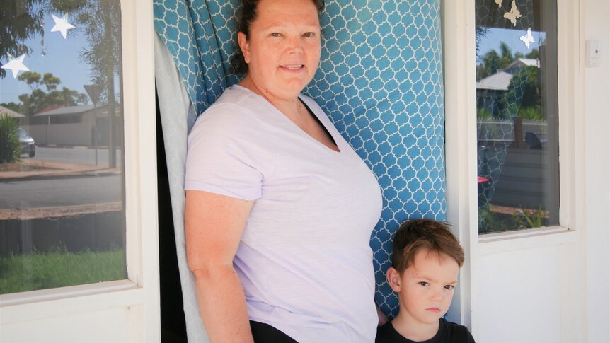 Mother Karen Davis with her son Macen standing outside front door of their home.