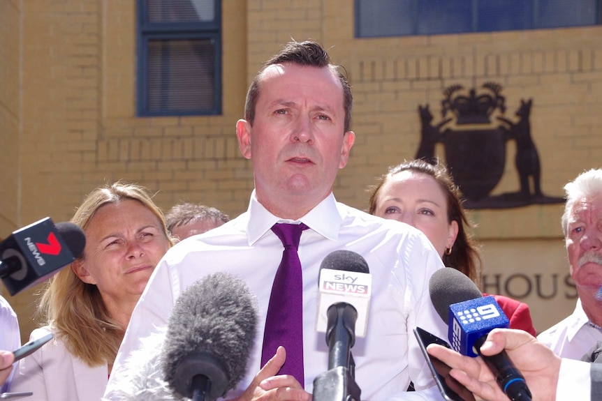 Mark McGowan surrounded by media.