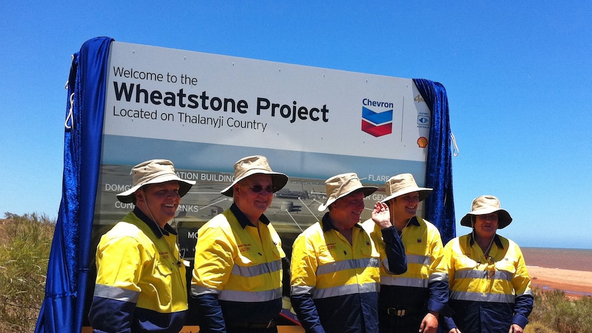 Workers stand in front of a sign at the official opening of Chevron's Wheatstone LNG project in the Pilbara