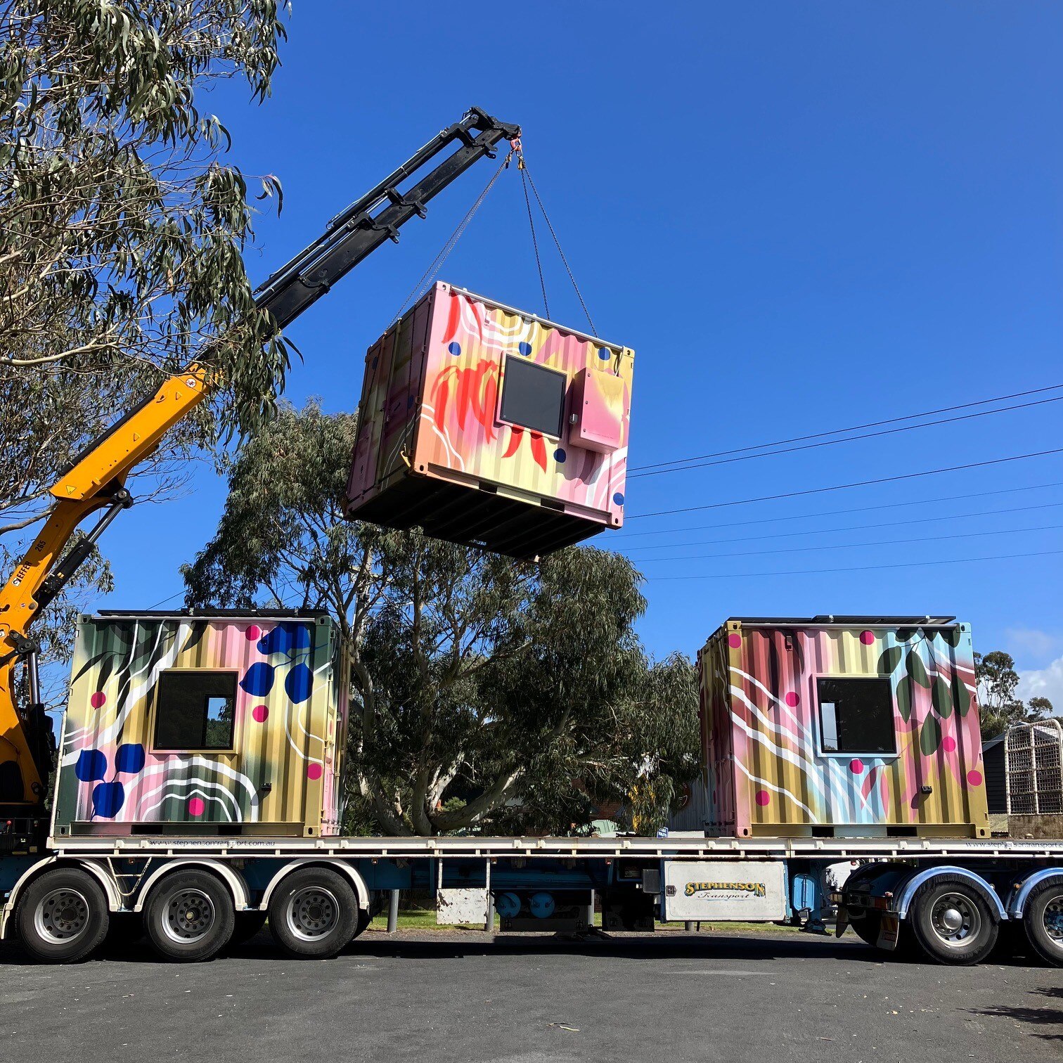 Crane carrying cube off a truck 