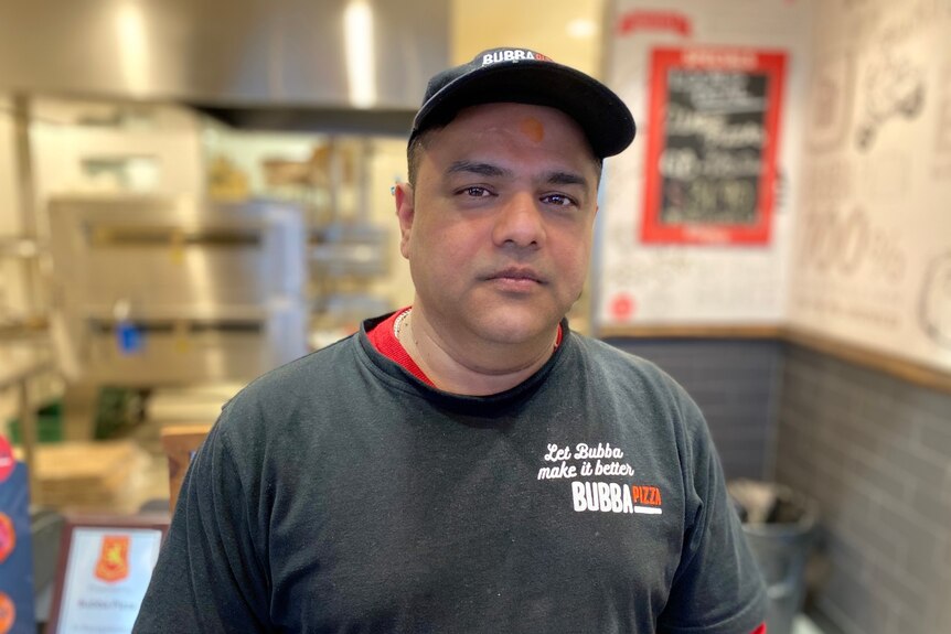 Atul Sharma wearing a grey Bubba Pizza t-shirt inside the restauraunt.