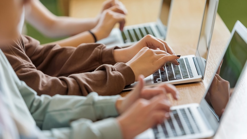 High school students sitting in a classroom using laptops