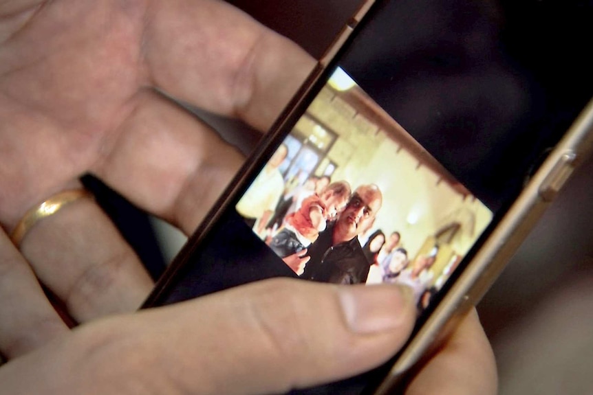 Hands hold a mobile phone featuring a picture of Mohammed Al Halabi.