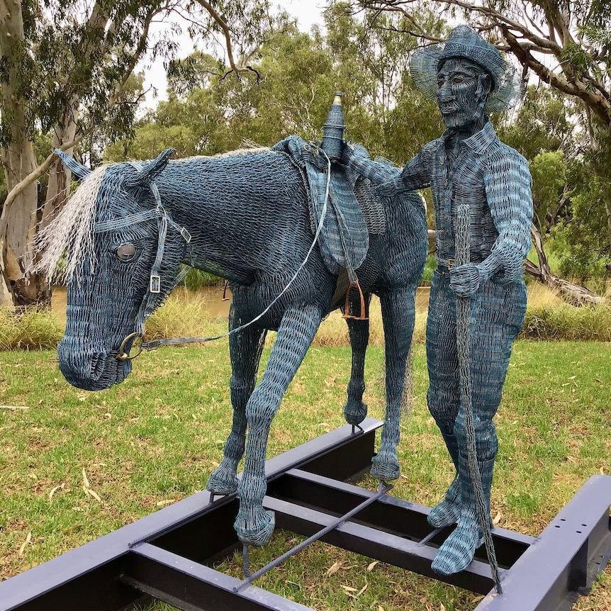 a metallic man and horse standing together