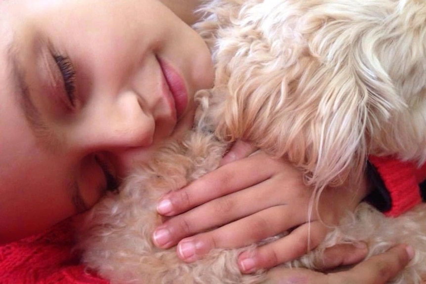 A close up of Priya's face against fur, hugging dog. 