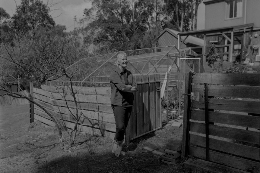 Woman stands in front of gate to garden 