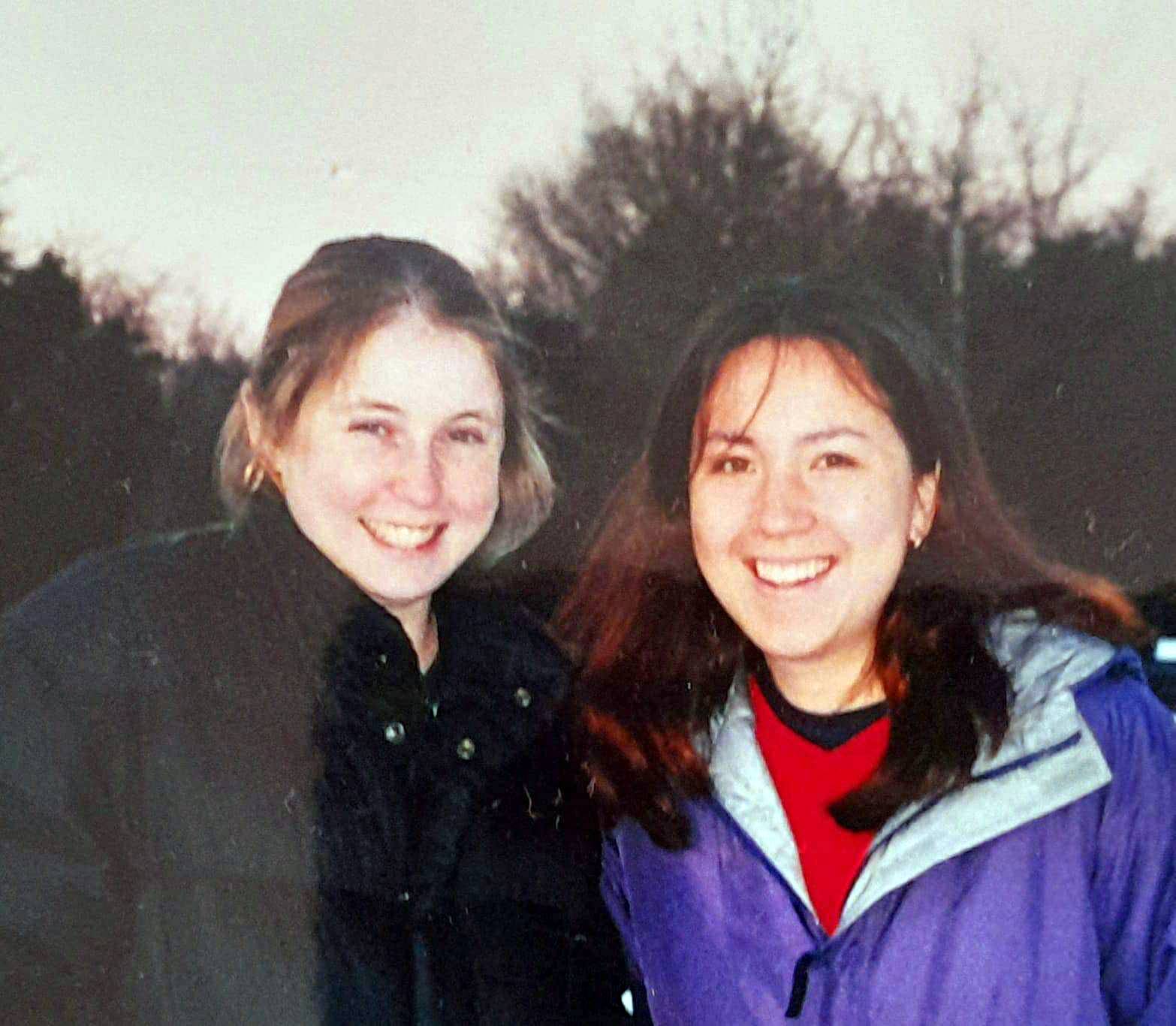 Two young women, wearing warm jackets, smiling.
