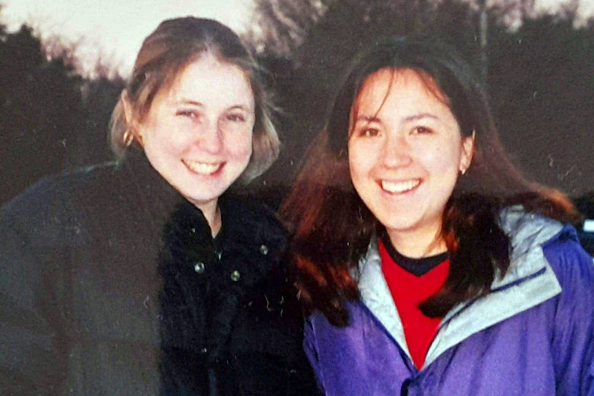 Two young women, wearing warm jackets, smiling.