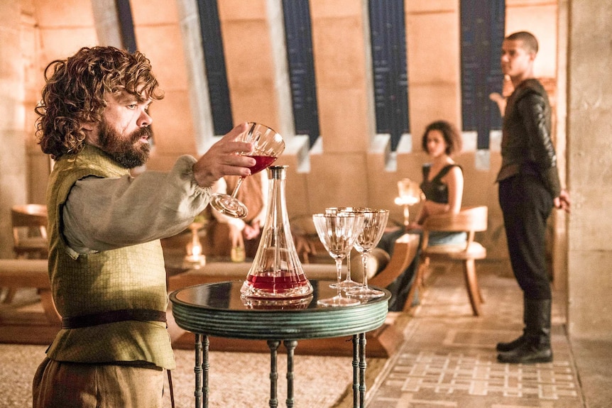 Tyrion Lannister in Game of Thrones season six pours a glass of wine.