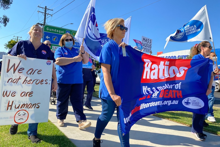 Nurses hold flags and signs during a strike. 