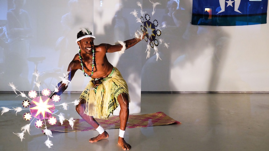 A Torres Strait Island dancer performs in an otherwise empty art gallery.