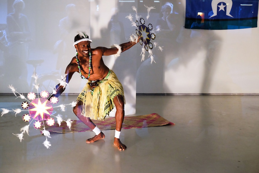 A Torres Strait Island dancer performs in an otherwise empty art gallery.