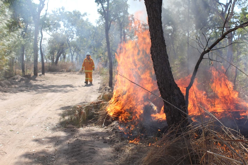 Firefighter walks behind a burning fire at Hell's Gate