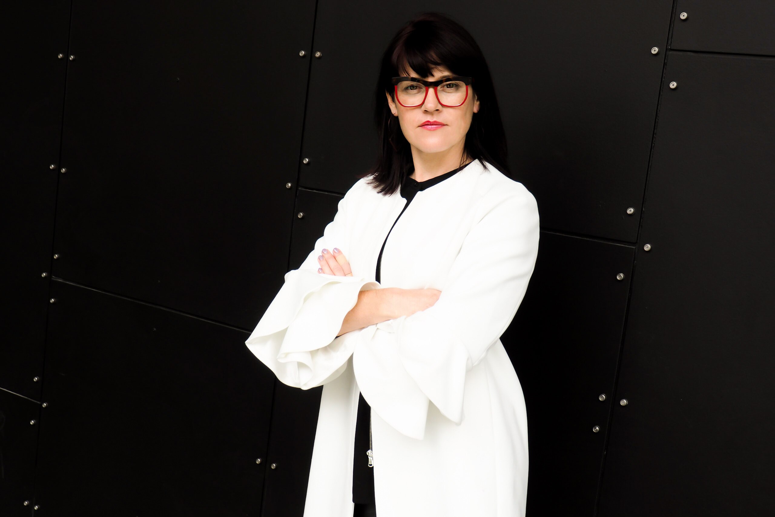 A woman in a white lab coat crossing her arms.