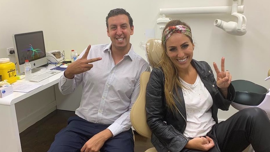 Dentist Ramy Georgy and a female contestant from the The Block pose doing peace signs in his dental office.