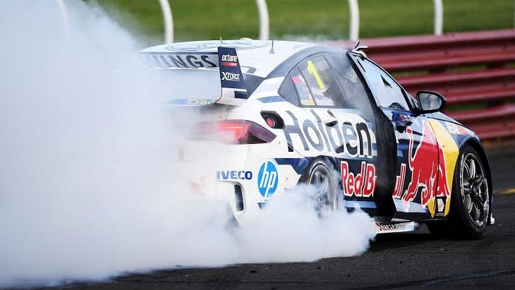 A racing car spins the rear wheels to create smoke.